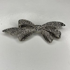 Brooch Bow in Silver Tone Metal With Rhinestone Center.